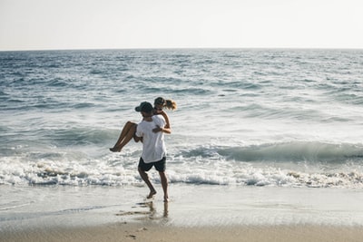 A man holding a woman on the beach
